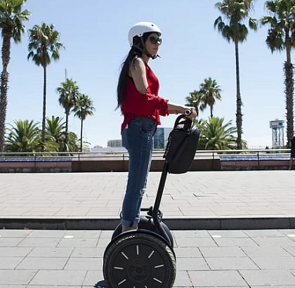 o persoana pe segway pe strada, se misca pe drum cu casca